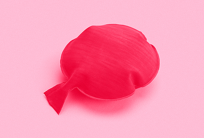 A red whoopee cushion on a pink background.