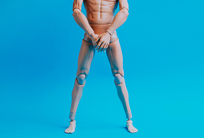 naked male doll covering genital region with hands on blue background