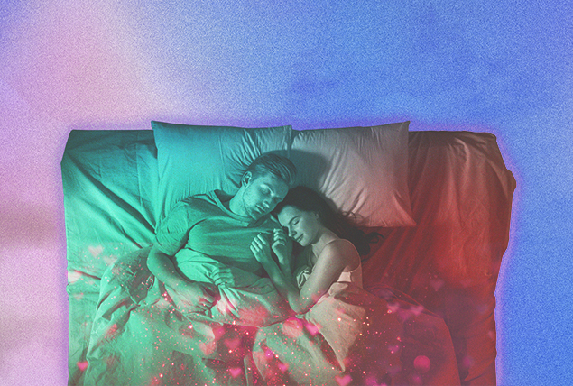 A couple sleeps on a bed together as a multicolor lay shines on them.