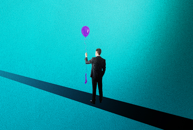 man stands on black stripe holding an inflated balloon and deflated balloon on blue background