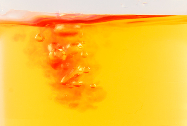 red liquid dropping into bright yellow liquid 