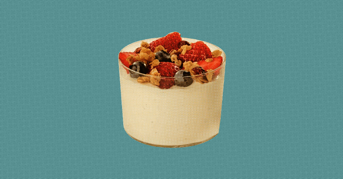 A yogurt parfait with granola and berries sits against a blue background.
