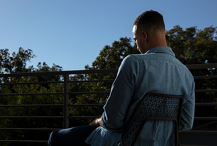 Man-sits-in-chair-facing-away-from-camera