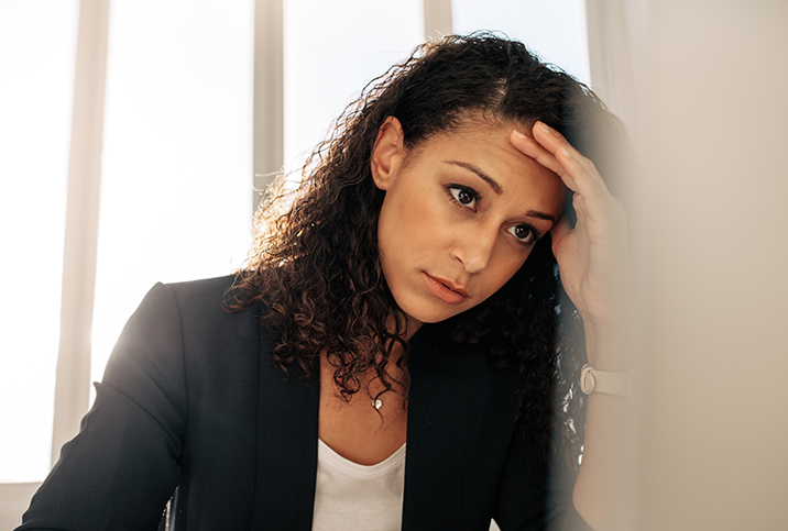 A stressed woman leans her head into her hand.