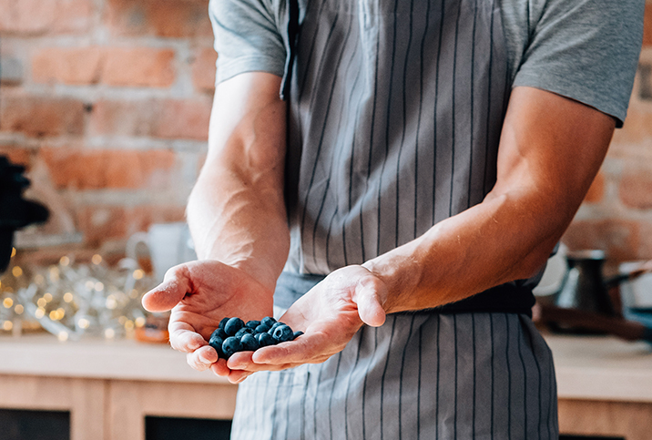 A man holds blueberries between two cupped hands.