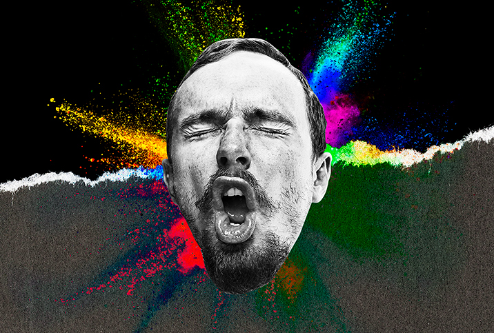 A man makes a face during an orgasm with multiple colors spraying from behind his head.