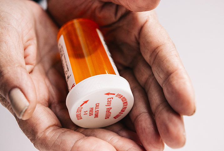 A pair of hands are holding an empty pill bottle.