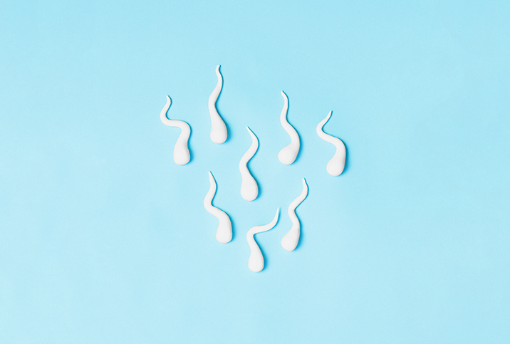 Eight sperm cells are swimming downward along a blue surface.