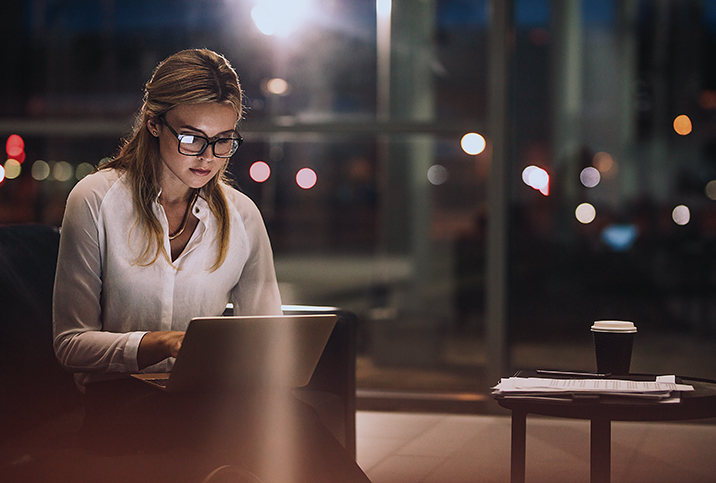 A woman works on her laptop in a coffeeshop at night.