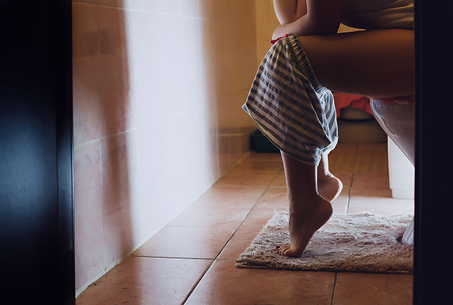 A woman sits on the toilet.