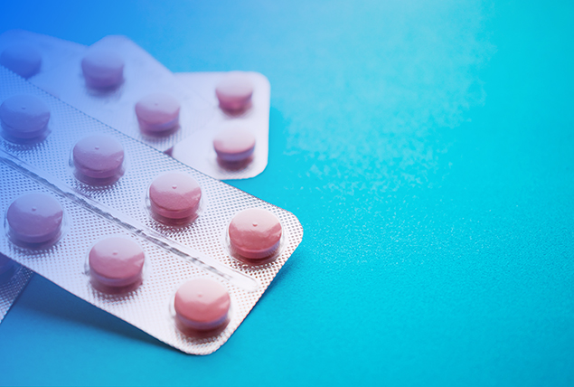 A packet of Statin pills lays against a blue surface.