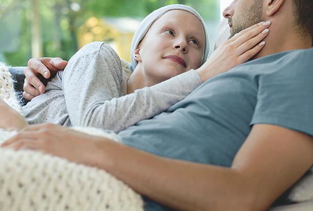 A woman with cancer cuddles up next to her partner.