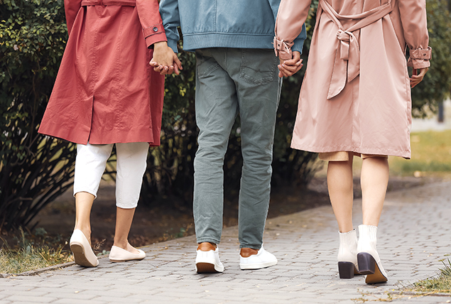 two women in raincoats holding hands and walking with one man in jeans