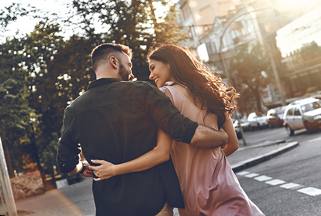 A couple walks away from the camera with an arm around each other's back.